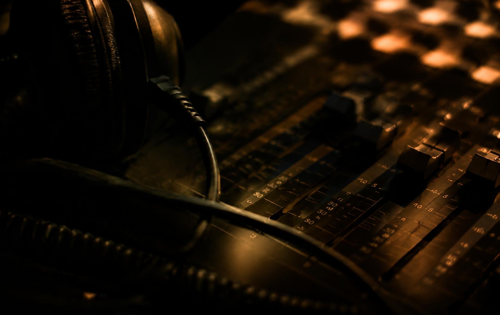 Mixing console faders and studio headphones in amber light